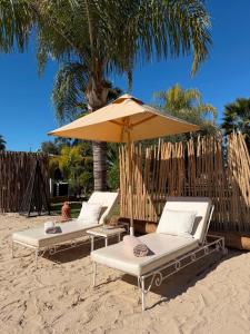 two lounge chairs and an umbrella on a beach at Les Villas du Douar in Azib Oulad Lâdem