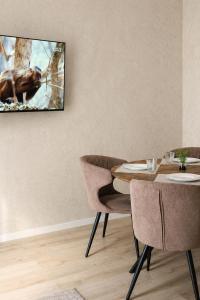 a dining room with a table and a tv on the wall at Simba Apartments Baile Felix in Baile Felix