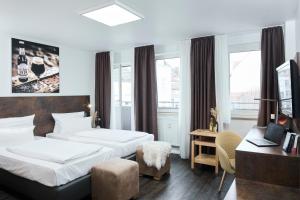 a hotel room with two beds and a desk at Altstadthotel Arte in Fulda