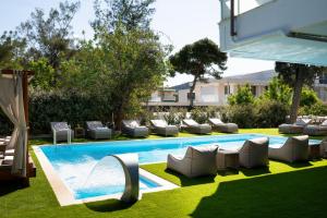 a swimming pool with chaises and chairs in a yard at Athenian Riviera Hotel& Suites in Athens