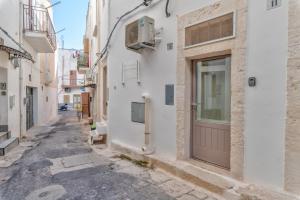 a narrow alley with a brown door in a white building at Ostuni Luxury Stay - 2 Jacuzzi in Ostuni
