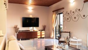 a living room with a tv on a wall at Ocean Breeze Apartment - Panoramic Sea View & Olive Grove - 100m to Beach in Kypseli