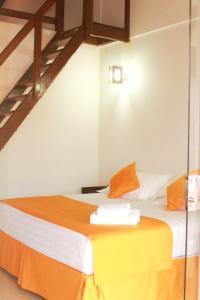 Habitación con cama con sábanas de color naranja y blanco. en Hotel Tierra Linda en San Ignacio de Velasco