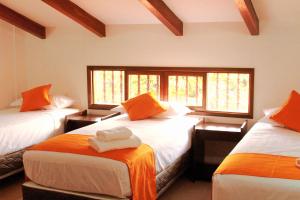 Habitación con 3 camas con sábanas de color naranja y blanco en Hotel Tierra Linda en San Ignacio de Velasco