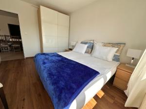 a bedroom with a large bed with a blue blanket on it at Appartement 2 chambres avec balcon terrasse in Villars-sur-Glâne