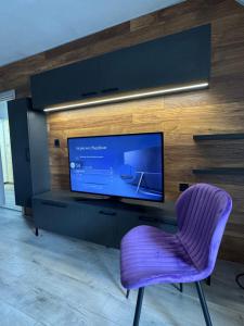 a purple chair in a living room with a tv at Aneva home in Ruse