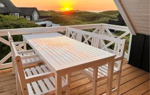 a white bench sitting on a deck with the sunset at Lovely Home In Saltum in Saltum