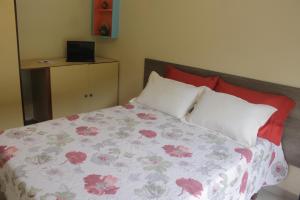 a bedroom with a bed with red and white pillows at O Melhor Chalé da Praia do Guaiúba, com Churrasqueira e Piscina Gigante in Guarujá +24 photos