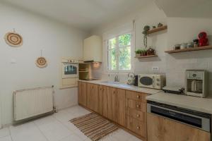 a large kitchen with wooden cabinets and a microwave at Joyful Secret Garden Residence Downtown by 8essentially in Chania