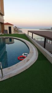 a swimming pool with a red boat next to a building at Mora by jodna - فندق مورا in Al Khobar