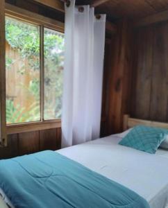 a bedroom with a bed with a window and a white bedspread at The Temple III, Mindo in Mindo