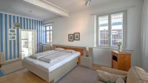 a bedroom with a bed and a chair and windows at Haus Thulboden in Heiligenhafen