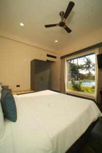 a bedroom with a large white bed and a window at Surf and Sand in Candolim
