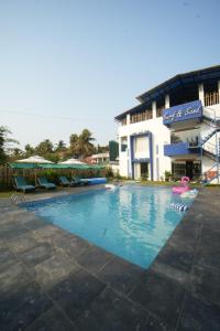 a swimming pool in front of a building at Surf and Sand in Candolim