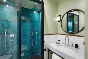 La salle de bains est pourvue d'une douche, d'un lavabo et d'un miroir. dans l'établissement Le Roch Hotel & Spa, à Paris