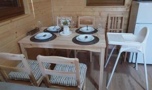 a dining room table with chairs and a white refrigerator at Drvena Oaza in Gornja Toplica