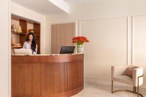 a woman standing at a reception desk with a laptop at Hotel Fori Imperiali in Rome