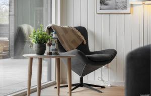 a black chair sitting next to a table with a plant at Beautiful Home In Ringkøbing With Sauna in Ringkøbing +18 photos