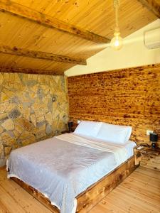 a bed in a room with a stone wall at Sandri Nature Lodge in Karahaxh