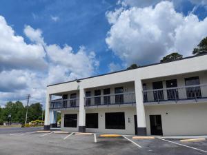 a large white building with a parking lot at Speedway Inn & Suites in Griffin