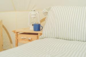a bed with a pillow and a bottle on a table at Boscoppa Farm-Emperor Tent No2 in Trethurgy