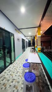 a swimming pool with tables and stools in a building at Kohlibong forest house in Trang