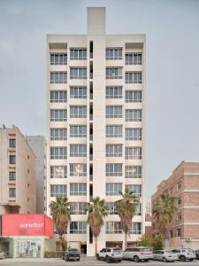 a large white building with palm trees in front of it at Hamad - Salmiya -Family only in Kuwait