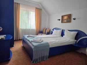 a bedroom with a blue and white bed and a window at Pensiunea Emma in Sâmbăta de Sus