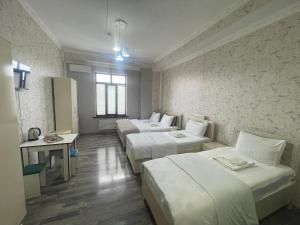a hotel room with three beds and a table at Delfin Hotel Restaurant Spa Ailevi in Ganja