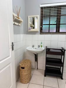 a white bathroom with a sink and a window at Tranquil Gardens in Pietermaritzburg +16 photos
