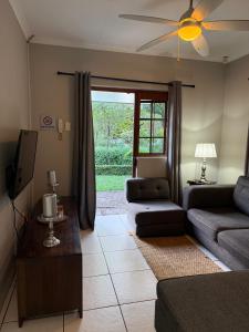 a living room with a couch and a tv at Tranquil Gardens in Pietermaritzburg
