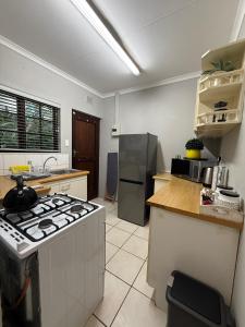 a kitchen with a stove and a refrigerator at Tranquil Gardens in Pietermaritzburg