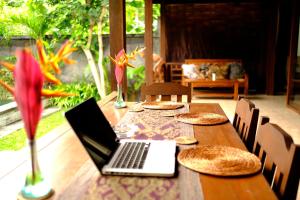 um computador portátil sentado em cima de uma mesa de madeira em Prama House em Ubud