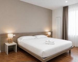 a bedroom with a large white bed with two lamps at Foresteria Via Italia - Rooms & Suite in Rho