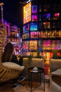 a woman sitting in a chair in front of a building at ZEN Suites Hotel Massira in Casablanca