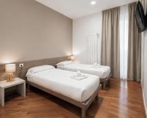a hotel room with two beds and a television at Foresteria Via Italia - Rooms & Suite in Rho