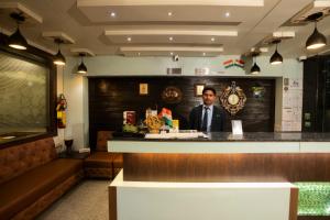 a man standing behind a bar in a restaurant at Hotel Shree Vatika in Bhopal