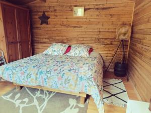 a bedroom with a bed in a wooden wall at Chalet dans notre jardin in Parigné