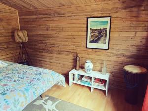 a bedroom with wooden walls with a bed and a night stand at Chalet dans notre jardin in Parigné