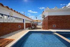 a swimming pool next to a building with an umbrella at Casa Vacacional Playa del Sur in Chichiriviche
