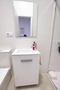a white bathroom with a sink and a mirror at Cuencaloft El 3 in Cuenca
