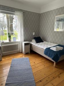 a bedroom with a bed and a window and a rug at Vadstena Folkhögskola Vandrarhem in Vadstena
