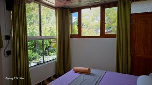 a bedroom with windows and a bed with a towel on it at Nature View Villa in Badulla