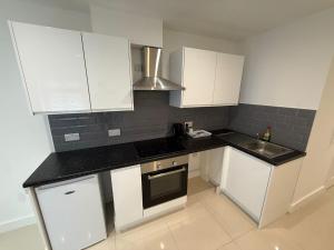 a kitchen with white cabinets and black counter tops at Radstock Road - Room 2 in Southampton