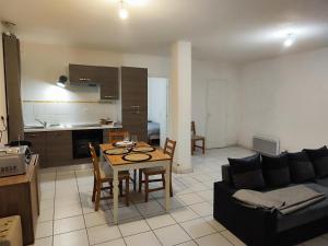 a kitchen and a living room with a table and a couch at L'Ecrin de l'Abreuvoir in Marnay