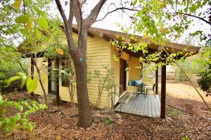 a small yellow house with a wooden porch at בקתות נומה in Moshav Ramot