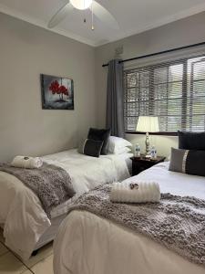 a bedroom with two beds and a window at Tranquil Gardens in Pietermaritzburg