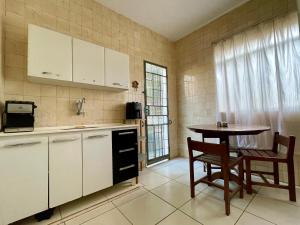 a kitchen with white cabinets and a table and chairs at Casa Jardim Centro in Patos de Minas