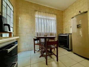 a small kitchen with a table and a refrigerator at Casa Jardim Centro in Patos de Minas