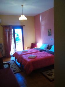 una camera da letto con un letto con un piumone rosso e una finestra di Hotel Aoos a Konitsa